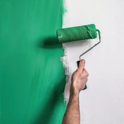 Hand painting a wall with green paint using a roller, representing paints and coatings