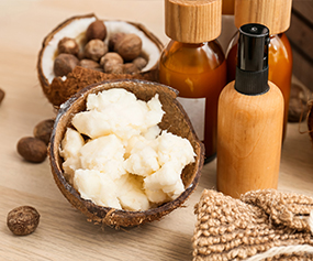 Exotic butter in a bowl with skincare bottles and natural ingredients for deep hydration and luxurious texture